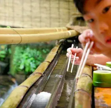 Un enfant essayant d'attraper des nagashi sômen.