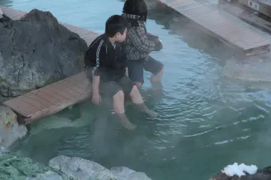 Des enfants se trempent les pieds dans les eaux chaudes de la rivière Kawayu