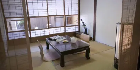 In the back of the room, shoji, transparent sliding doors, separate the rooms with a view of the garden outside.