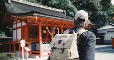 Homme avec son sac à dos devant un temple japonais
